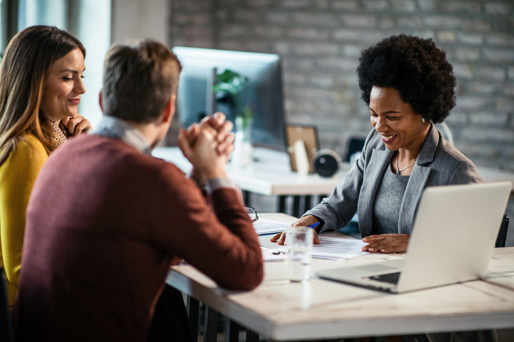 Cheerful African American financial advisor on a meeting with a couple. Happy African American insurance agent going through reports while having consultations with a couple during the meeting. About BlueStone Services